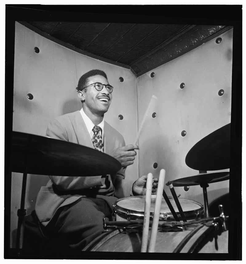 Black and white photo of Max Roach playing the drums by William Gottlieb.