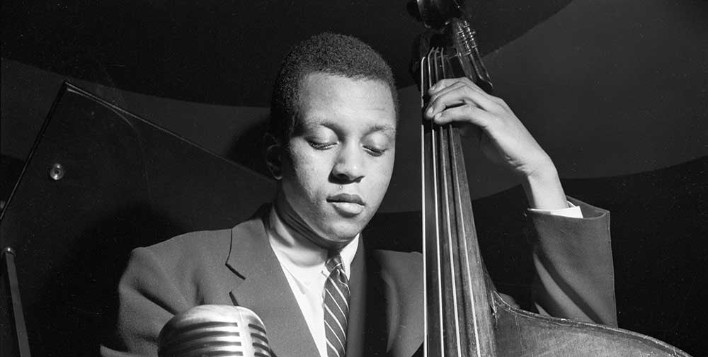 Black and white portrait by Francis Wolff of jazz musician Doug Watkins playing bass.