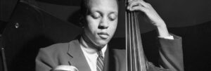 Black and white portrait by Francis Wolff of jazz musician Doug Watkins playing bass.