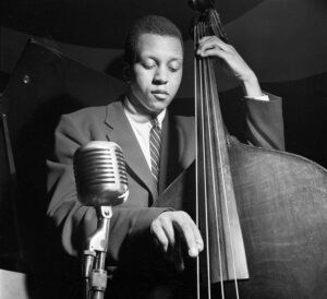 Black and white portrait by Francis Wolff of jazz musician Doug Watkins playing bass.